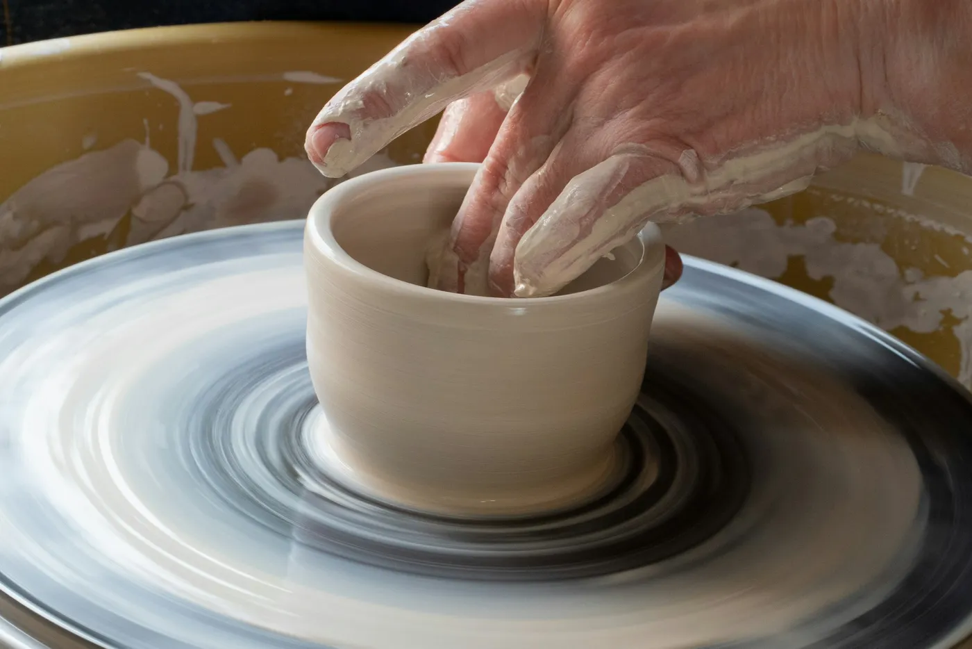 A potter shaping a cup on a pottery wheel