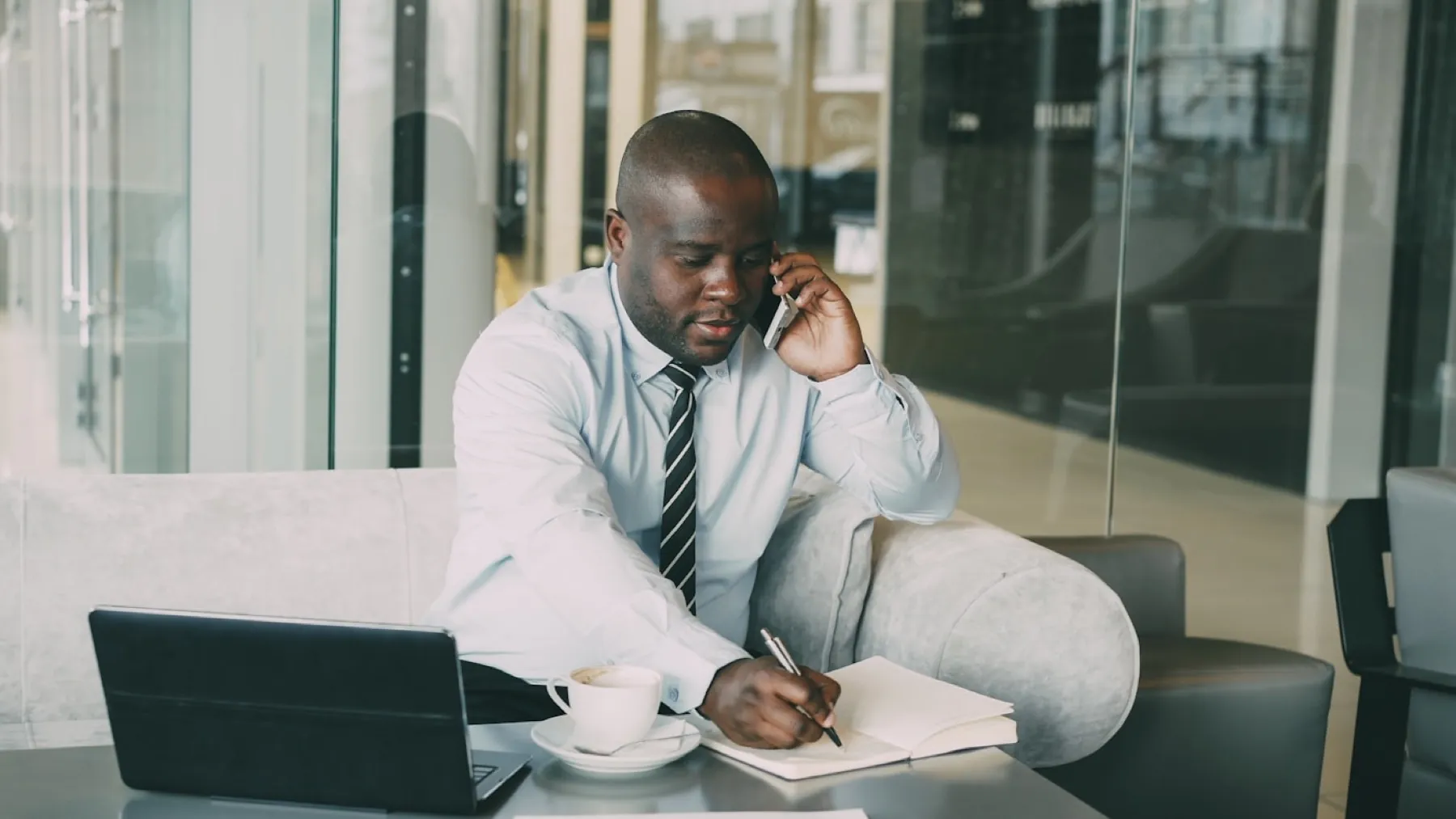 A business owner taking notes on a call while working at a laptop